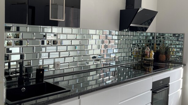 Una cocina moderna con una paleta de colores blanco y negro, un lavamanos de acero inoxidable y un horno empotrado.