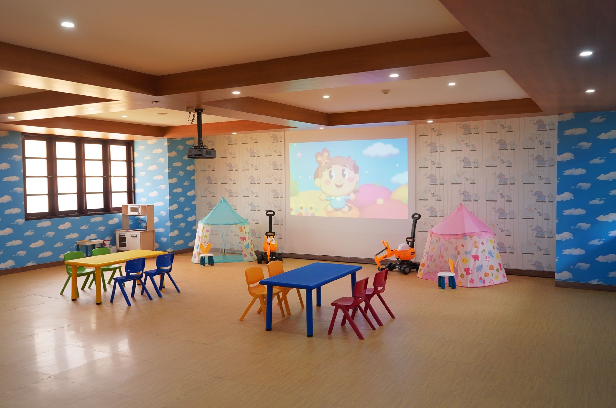 Une salle de jeux pour enfants avec des tables, des chaises et des tentes de jeu.