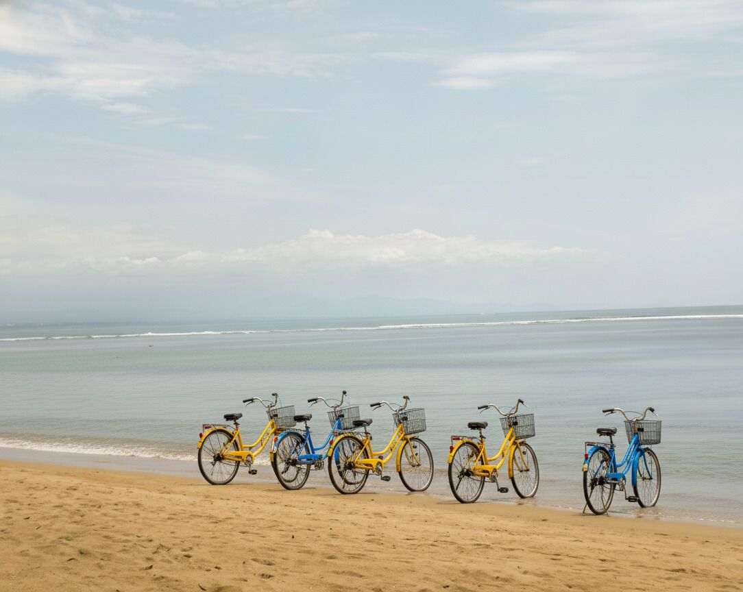 Varias bicicletas alineadas en una playa arenosa, con el océano al fondo.
