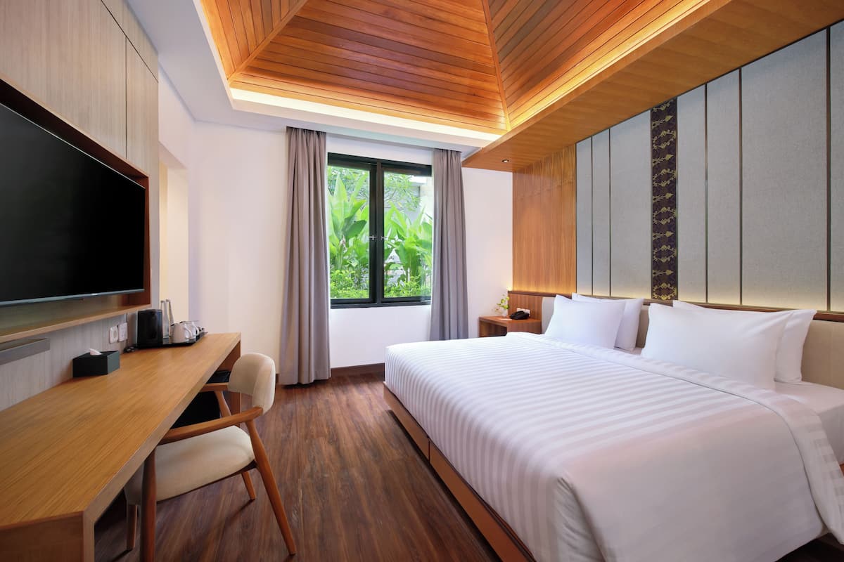 A modern hotel room with a wooden desk, a large bed, and a television.