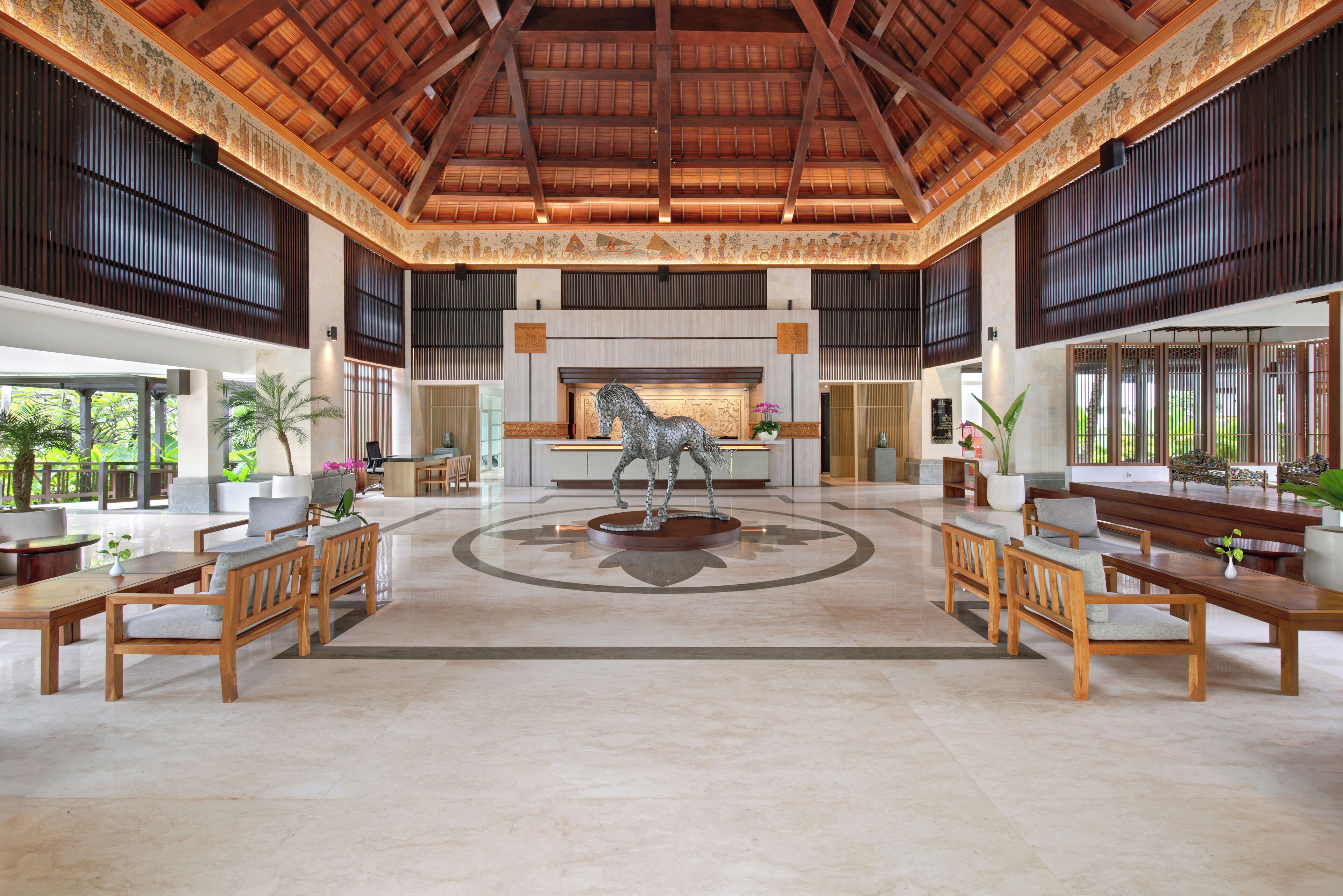 A spacious lobby with a high ceiling, a central fireplace, and a horse statue.