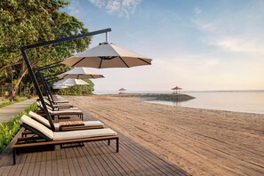 A wooden deck with lounge chairs and umbrellas overlooking a beach. - eL Hotel & Resort Bali Sanur (Denpasar)