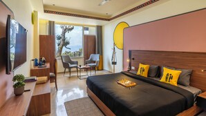 Habitación de hotel moderna con una cama grande, un escritorio, una silla, un televisor y un balcón con vistas.