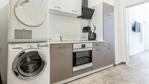 A compact kitchen with a built-in washer, dryer, microwave, and oven. - Lovely Apartment Steps from Schonbrunn (Vienna)