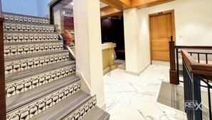 A staircase with ornate black and white patterns, leading to a reception area with a signboard and a wooden door. - Hotel Park Wood - Mall Road  (Mussoorie)