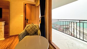 A room with a balcony, a wooden door, a round table, and a view of a cityscape. - Hotel Park Wood - Mall Road  (Mussoorie)