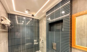 Ein Badezimmer mit dunkelblauen Fliesenwänden, einem spiegelnden Holzrahmen und einem Handtuchhalter.