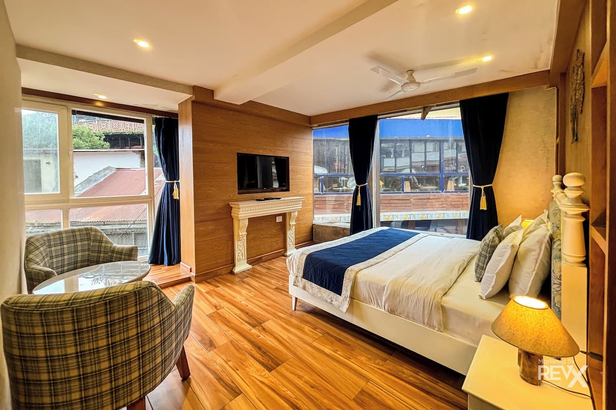 Ein Hotelzimmer mit Bett, Fernseher, Kamin, Stuhl und einem fenster mit Vorhängen.