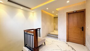 A modern interior with a wooden door marked "202", a marble staircase, and a railing with a bench. - Hotel Park Wood - Mall Road  (Mussoorie)