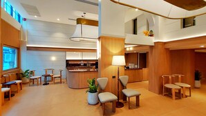 Eine Hotlellobby mit einer Rezeption, einer Sitzecke und einem großen Fenster.