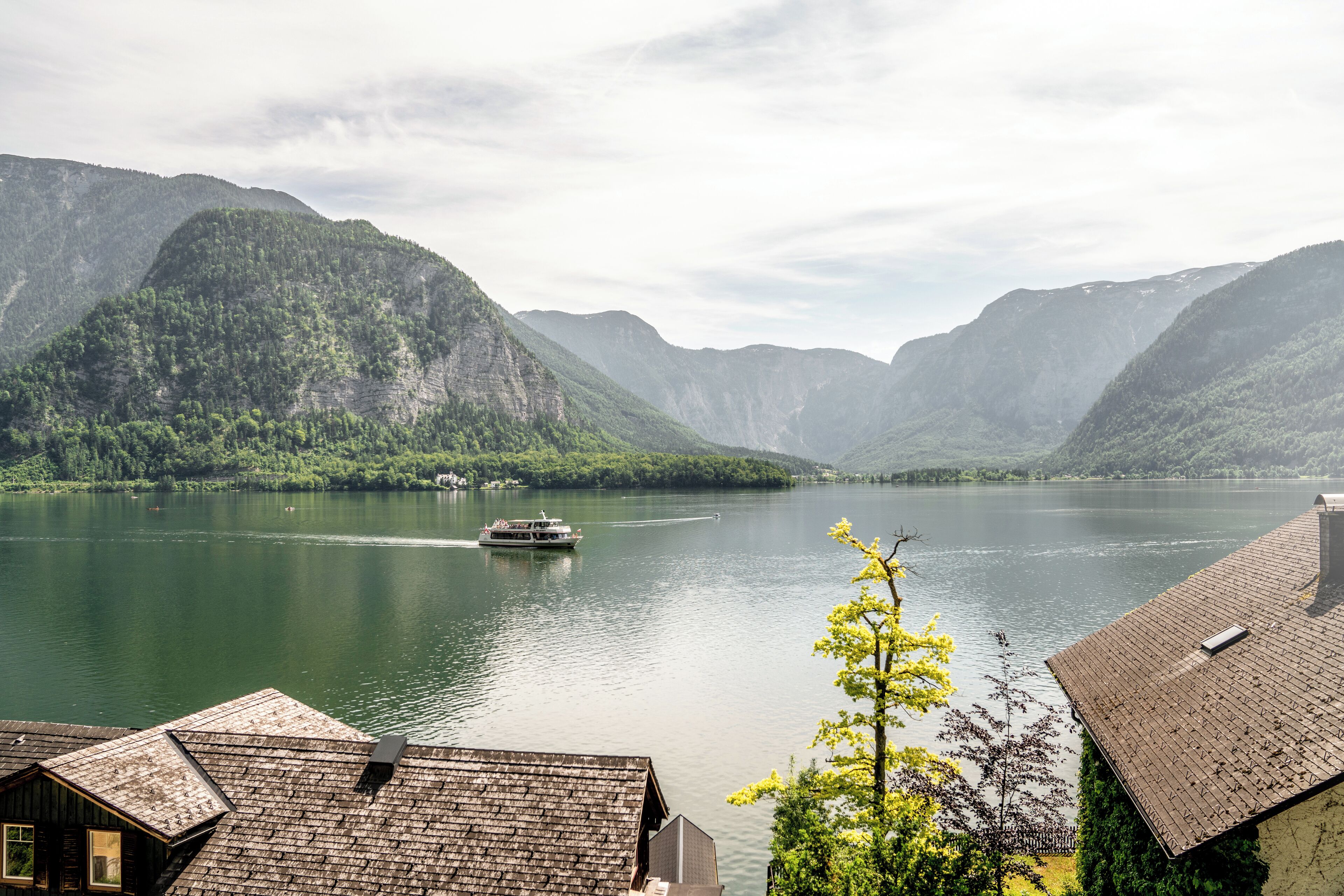 A lake with a boat, surrounded by mountains and houses with sloped roofs.