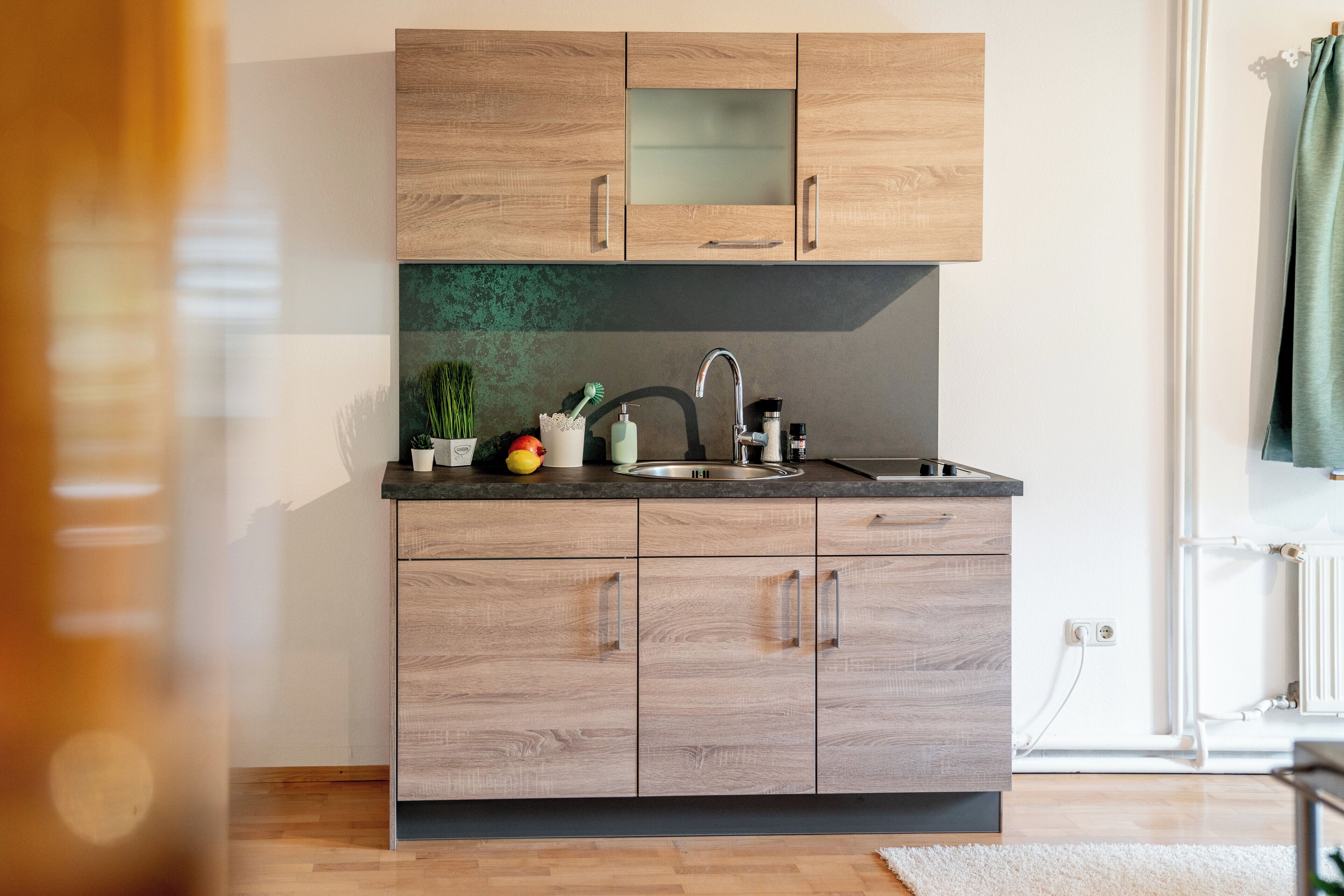 A modern kitchen with wooden cabinets, a stainless steel sink, and a countertop with various items.