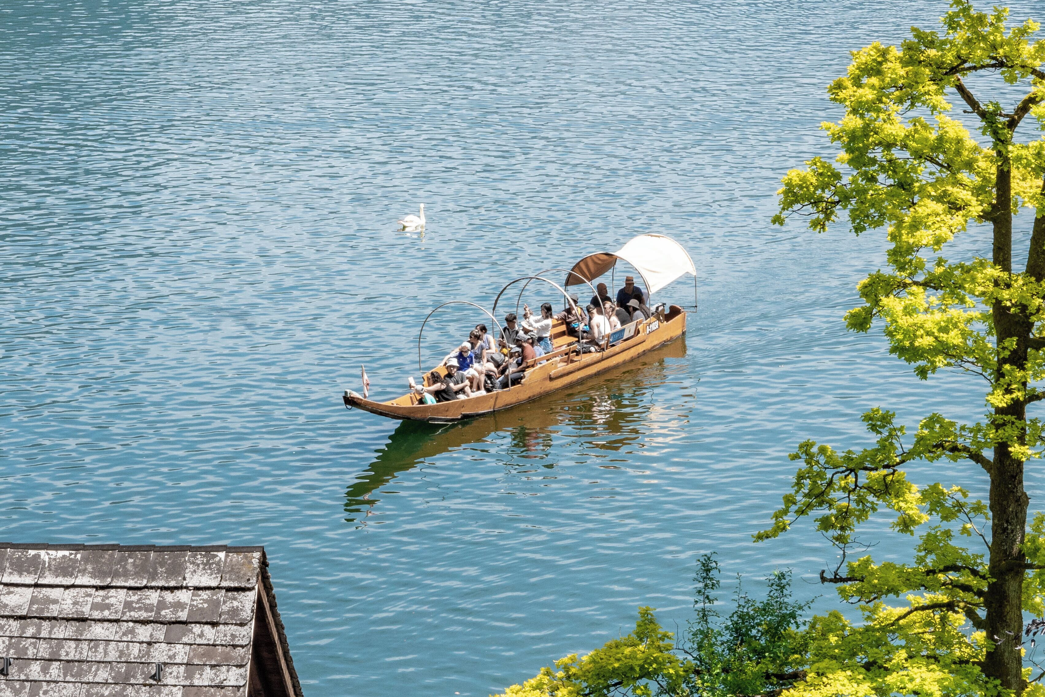 A wooden boat with passengers, floating on calm water.