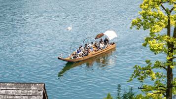 A wooden boat with passengers, floating on calm water.