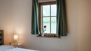 A bedroom with a bed, a nightstand with a lamp, a window with curtains, and a sign that says "Relax". - Lakeview Apartments (Hallstatt)