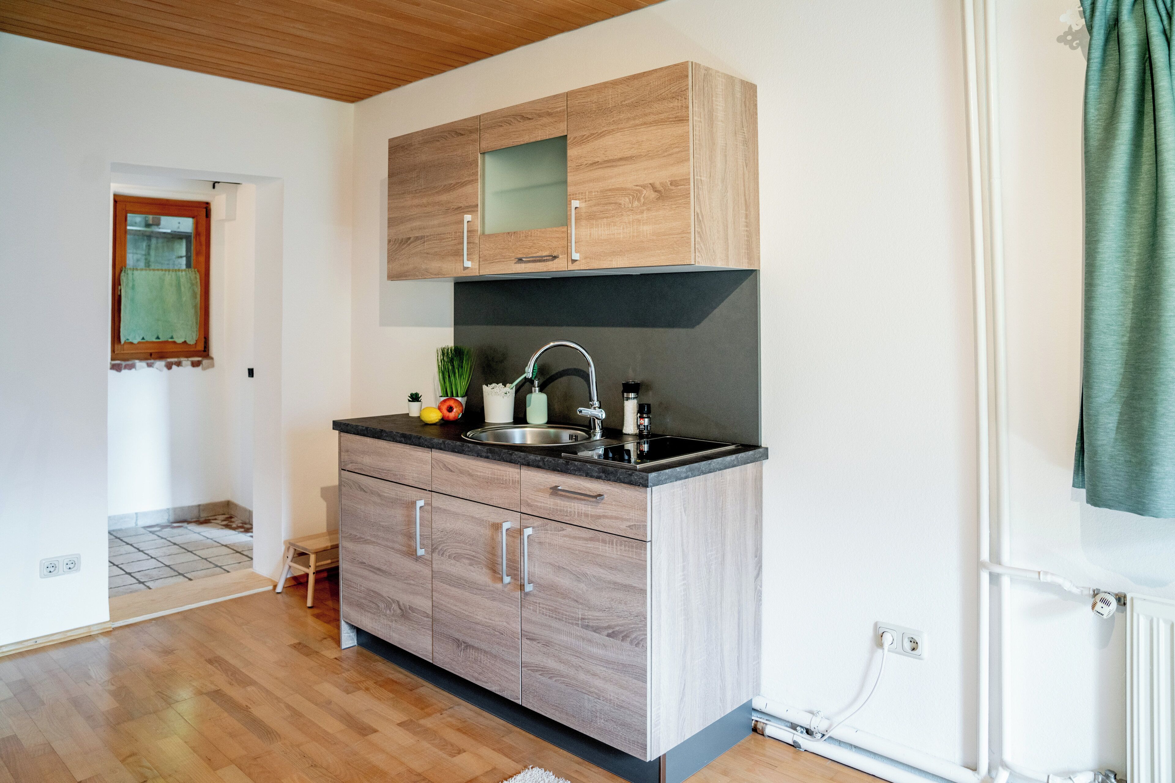 A modern kitchen with wooden cabinets, a black countertop, and a stainless steel sink.