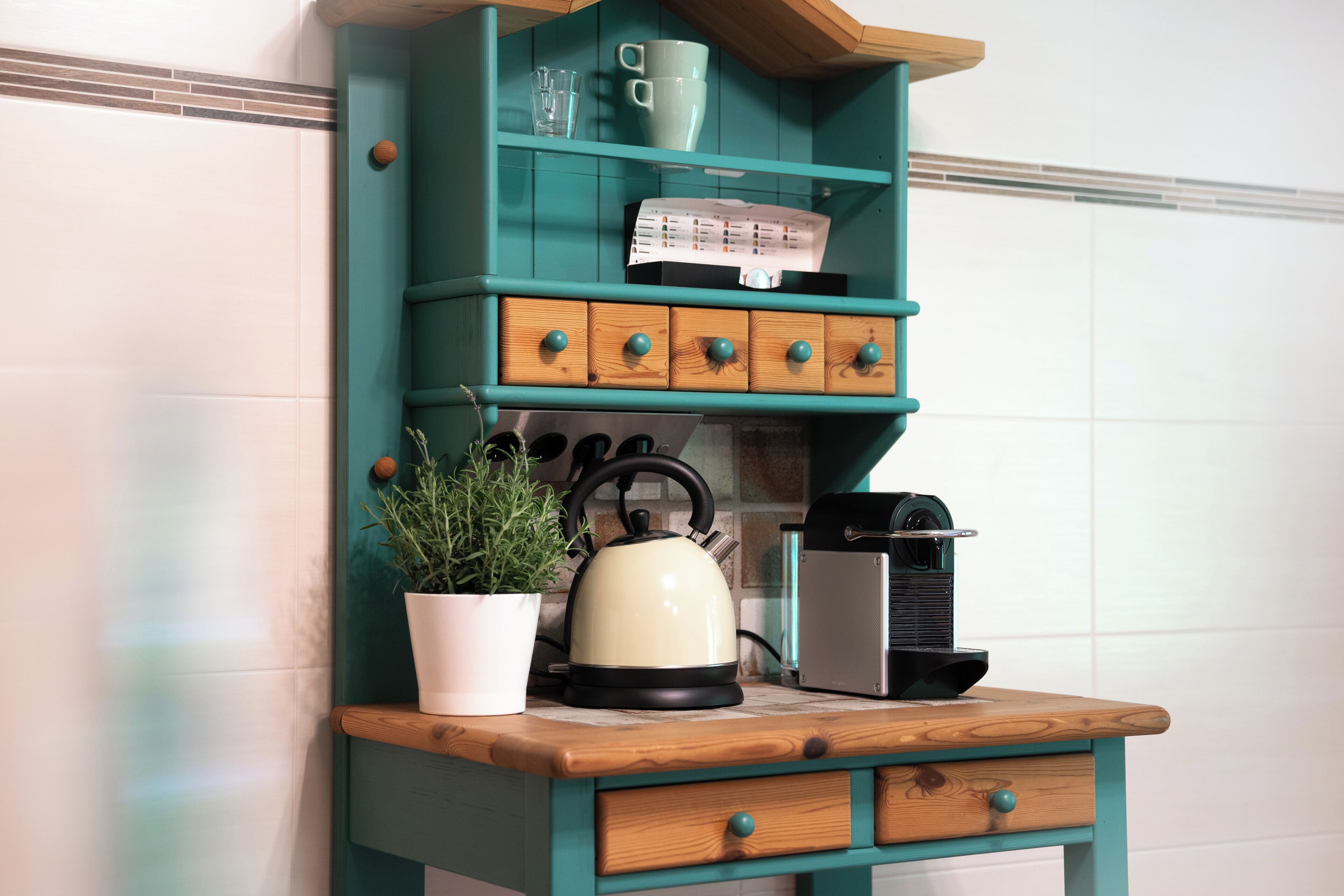 A kitchen counter with a kettle, a toaster, and a potted plant.