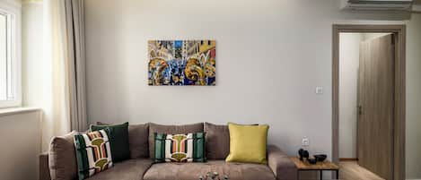 Un salon moderne avec un canapé marron, une table basse et un tableau abstrait aux couleurs vives accroché au mur.