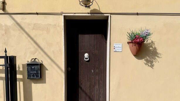 A door with a sign indicating 'Posta' and a flower pot on the wall. - Paint House (Imperia)