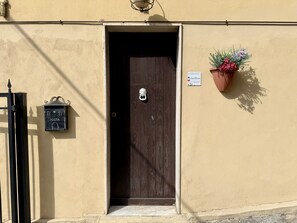 A door with a sign indicating 'Posta' and a flower pot on the wall. - Paint House (Imperia)