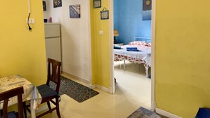 A room with a bed, a desk, and a chair. There is a door leading to another room. - Paint House (Imperia)