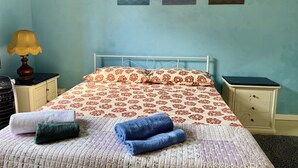A bedroom with a bed, two nightstands, a lamp, and three wall art pieces depicting different scenes. - Paint House (Imperia)