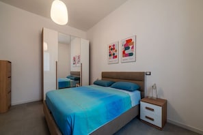 A bedroom with a bed, nightstand, and wardrobe.