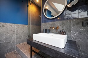 A modern bathroom with a white sink, dark tiles, and a blue accent wall. - Dünenloft, House Kliff Whg. 12 - Dünenlofts (Sylt)