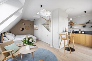 A modern loft apartment with a loft bed, a dining area, a kitchen, and a staircase. - Dünenloft, Haus Kliff, Whg. 9 - Dünenlofts (Sylt)