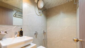 A bathroom with a white sink, a mirror, a handheld showerhead, and a toilet.