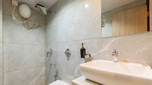 A modern bathroom with a large sink, a shower, and a toilet.