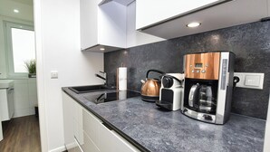 Una cocina moderna con encimera negra, electrodomésticos de acero inoxidable y un hervidor de cobre.