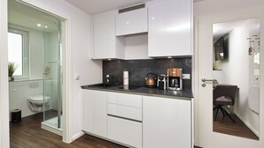 Una cocina moderna con armarios blancos, encimera negra y una cafetera.