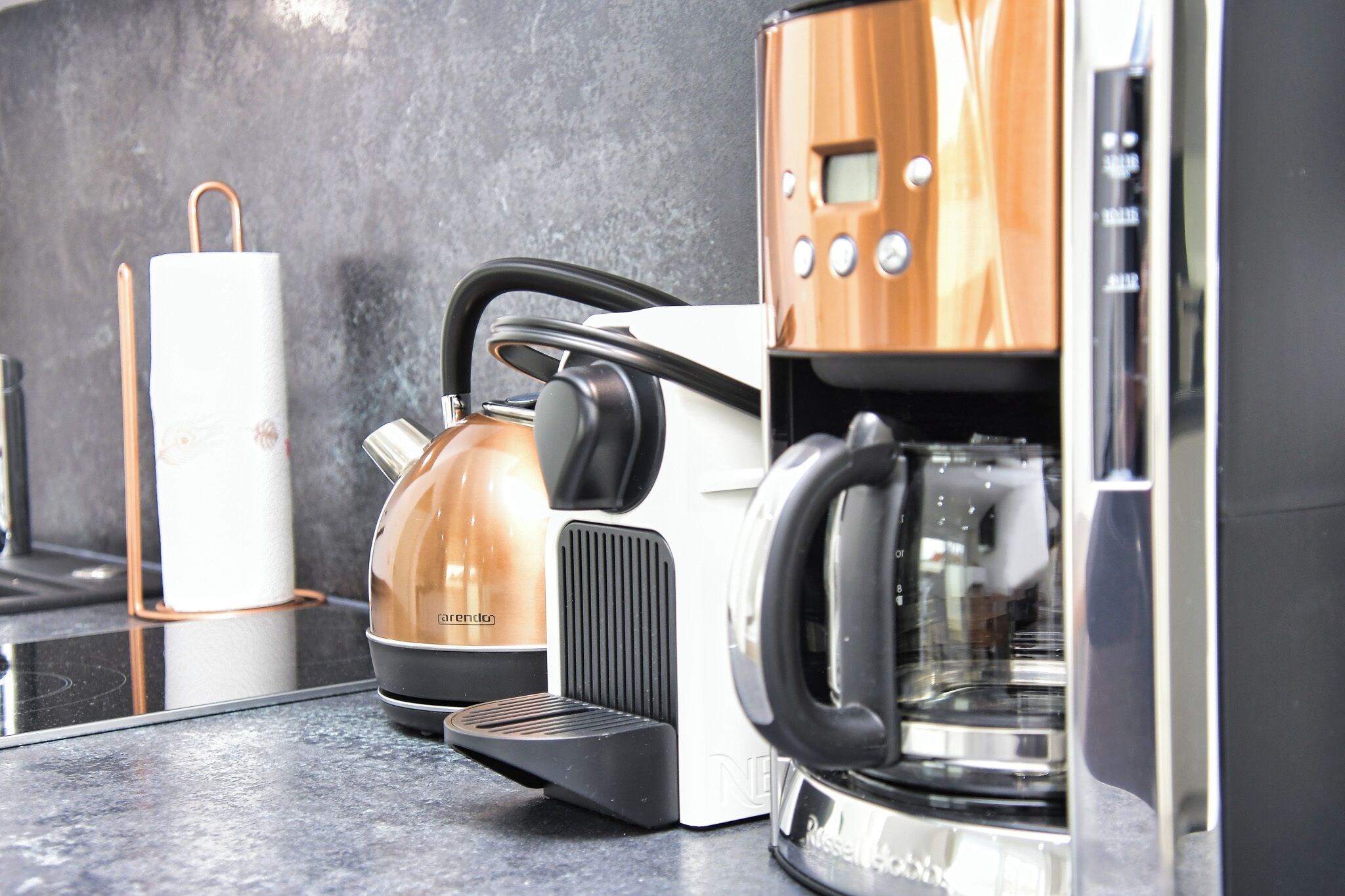 Ett modernt kök med en kaffebryggare, vattenkokare och en espressomaskin.