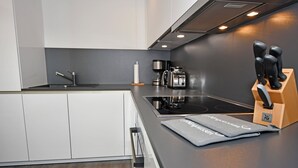 Et moderne køkken med sort bordplade, hvide skabe og et indbygget komfur.