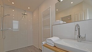 A modern bathroom with a walk-in shower, a large sink, and a towel rack. - Island Feeling Apartment 3 (Büsum)