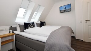 A modern bedroom with a bed, a desk, and a window. - Island Feeling Apartment 3 (Büsum)