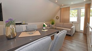 Ein modernes Wohnzimmer mit Essbereich, inklusive Sofa, Couchtisch und Esstisch mit Stühlen.