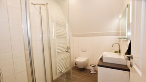 Een moderne badkamer met een douchecabine van glas, een toilet en een wastafel met spiegel.