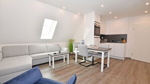 Een modern appartement met een woongedeelte, eethoek en keuken.