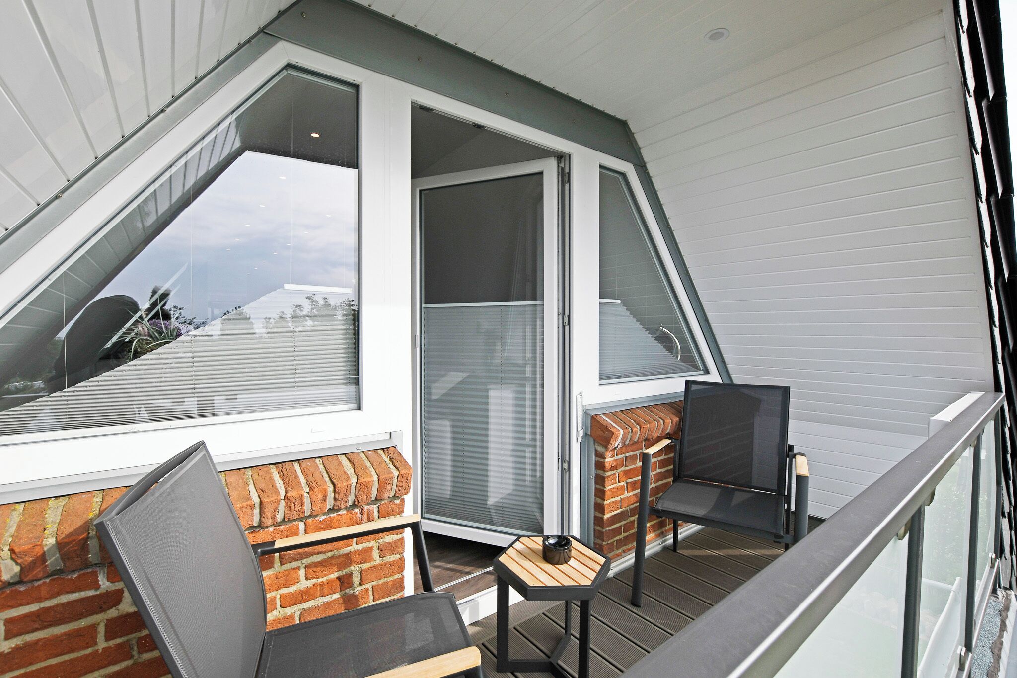 Un balcon donnant sur un paysage enneigé, un mur de briques et une porte vitrée.