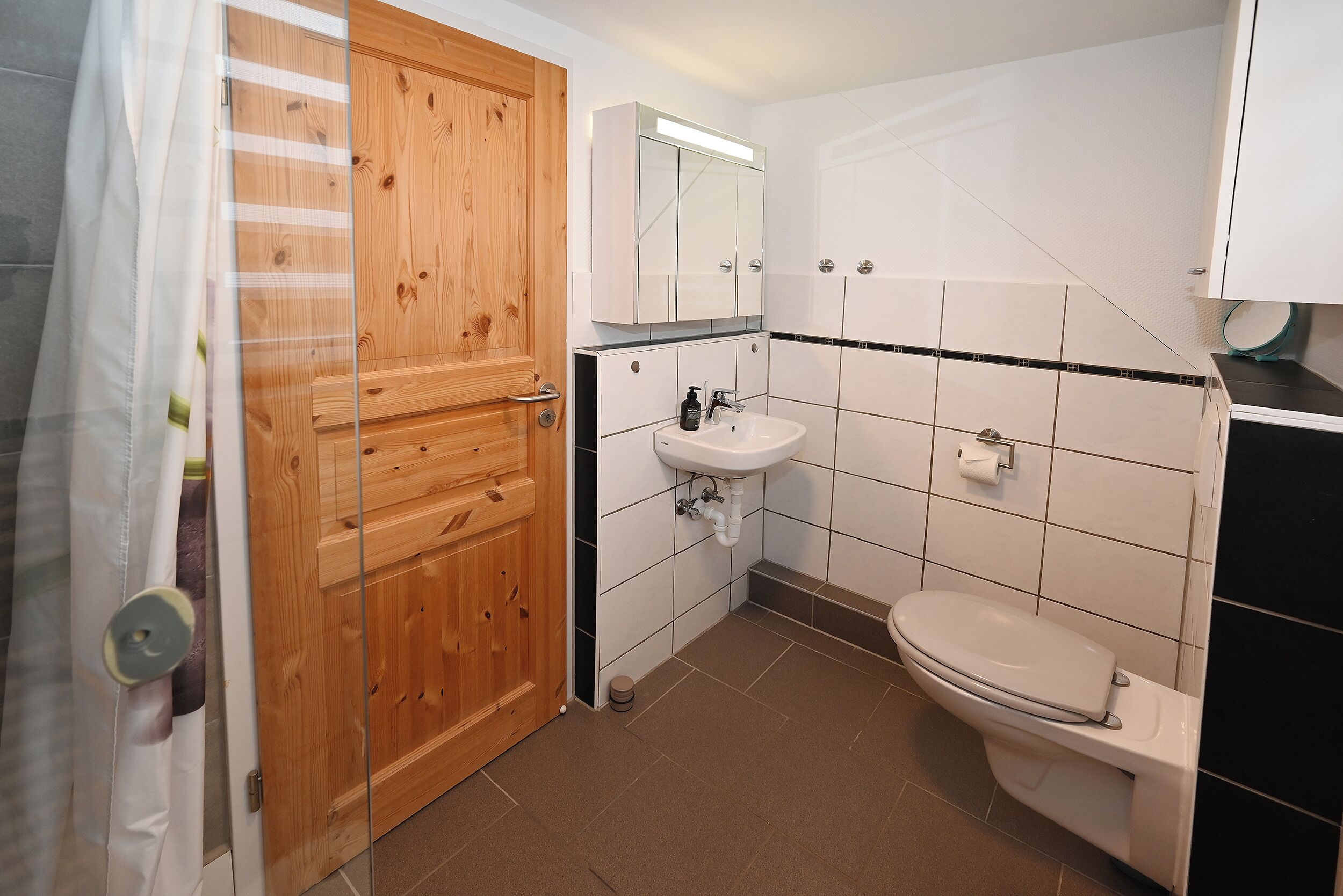 A bathroom with a wooden door, a sink, and a toilet.