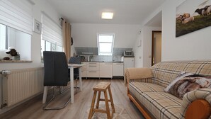 A compact living space with a kitchenette, a dining area, and a sofa. - Noah's Ark - House by the sea<br>Apartment Koog (Büsum)