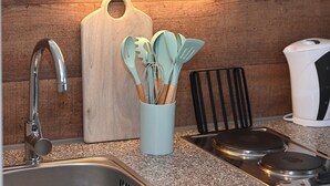 A kitchen with a wooden cutting board, a utensil holder, a sink, and a coffee maker. - Noah's Ark - House by the sea<br>Apartment Sea (Büsum)