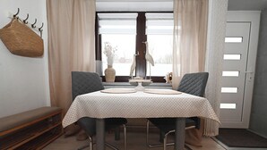 Een eetgedeelte met een tafel gedekt voor twee personen, een bank en een decoratief vogelsulptuur.