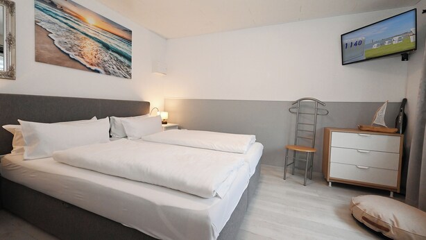 Een hotelkamer met een bed, een bureau, een stoel en een televisie aan de muur.