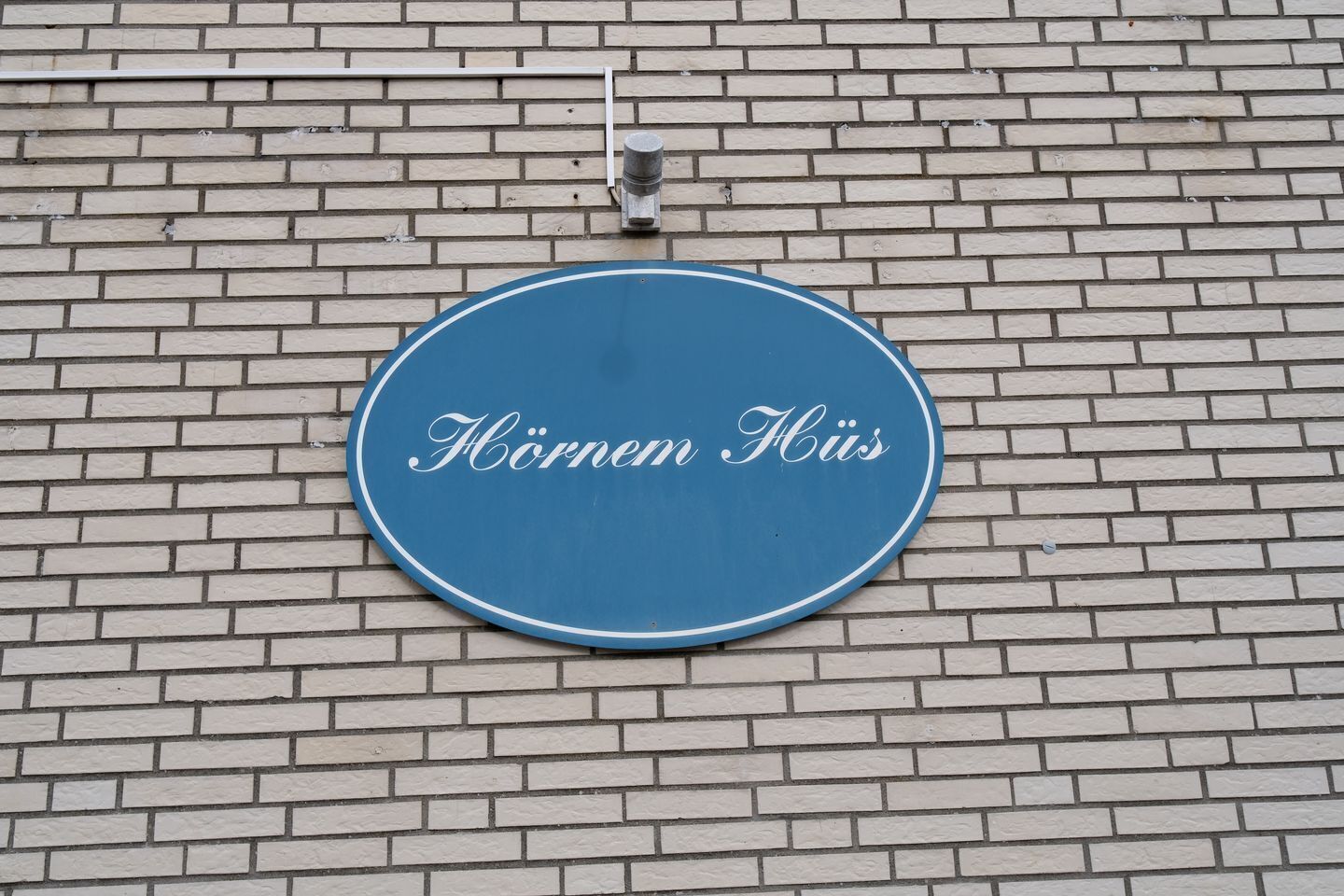 A blue sign with the text "Hörnen Hüs" on a brick wall.