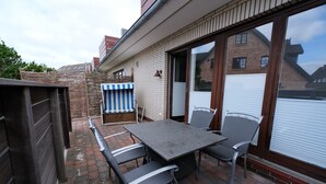 Un patio con una mesa y sillas, una silla de playa a rayas y una valla de madera.