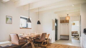 Een eetgedeelte met een houten tafel, stoelen, hanglampen en een bank.