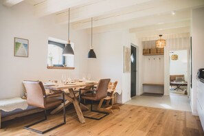 Ein Essbereich mit Holztisch, Stühlen, Pendelleuchten und einer Bank.